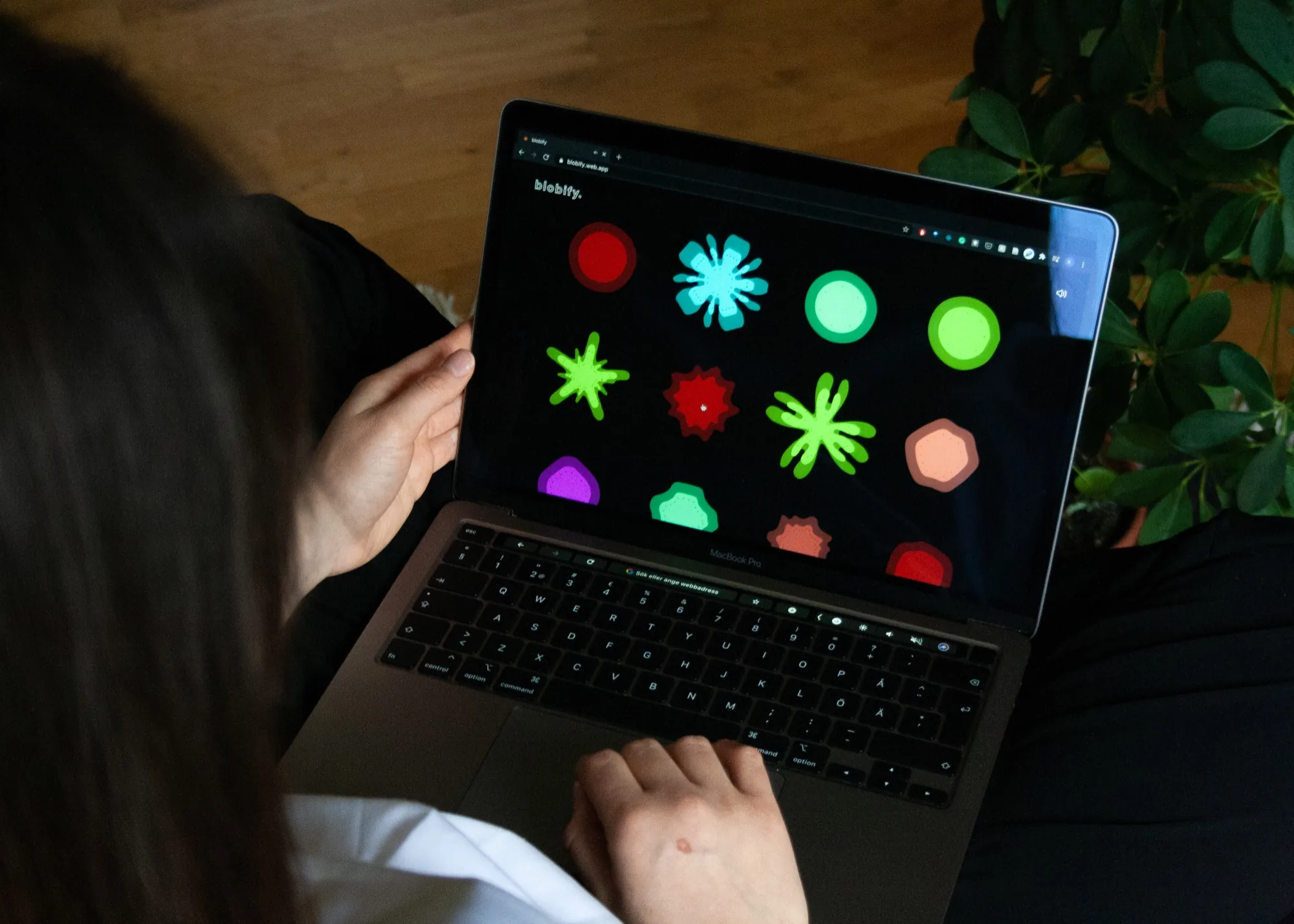 Someone using Blobify on a laptop, the screen showing a grid of bright animated blobs