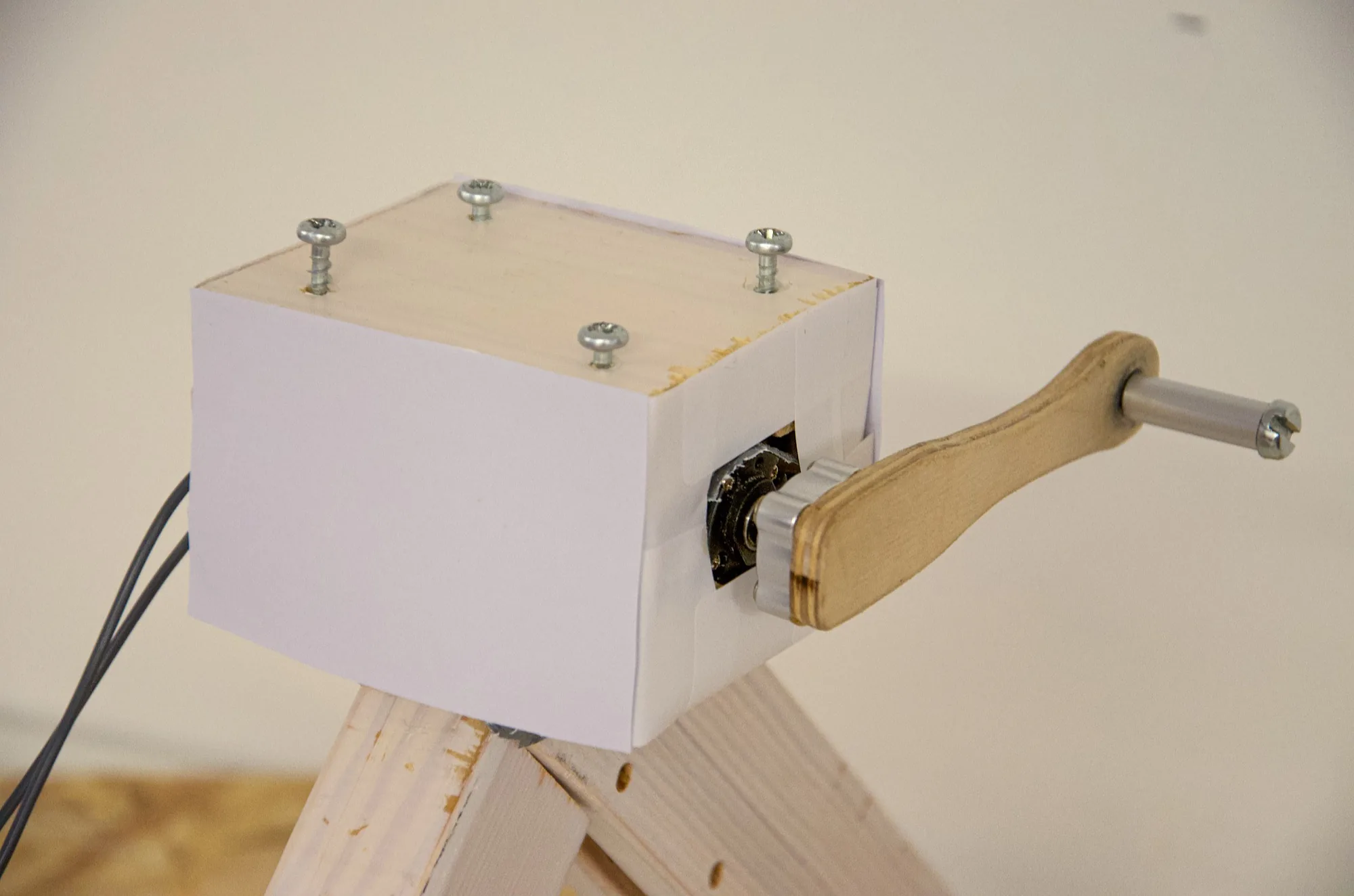 Close-up of the wooden crank handle connected to the generator housing