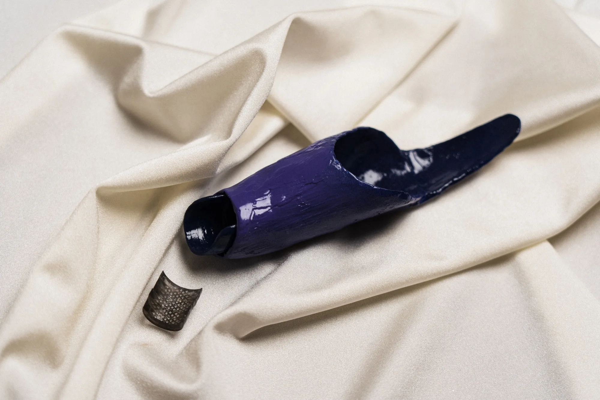 The purple silicone test applicator resting on cream fabric beside its mesh cap