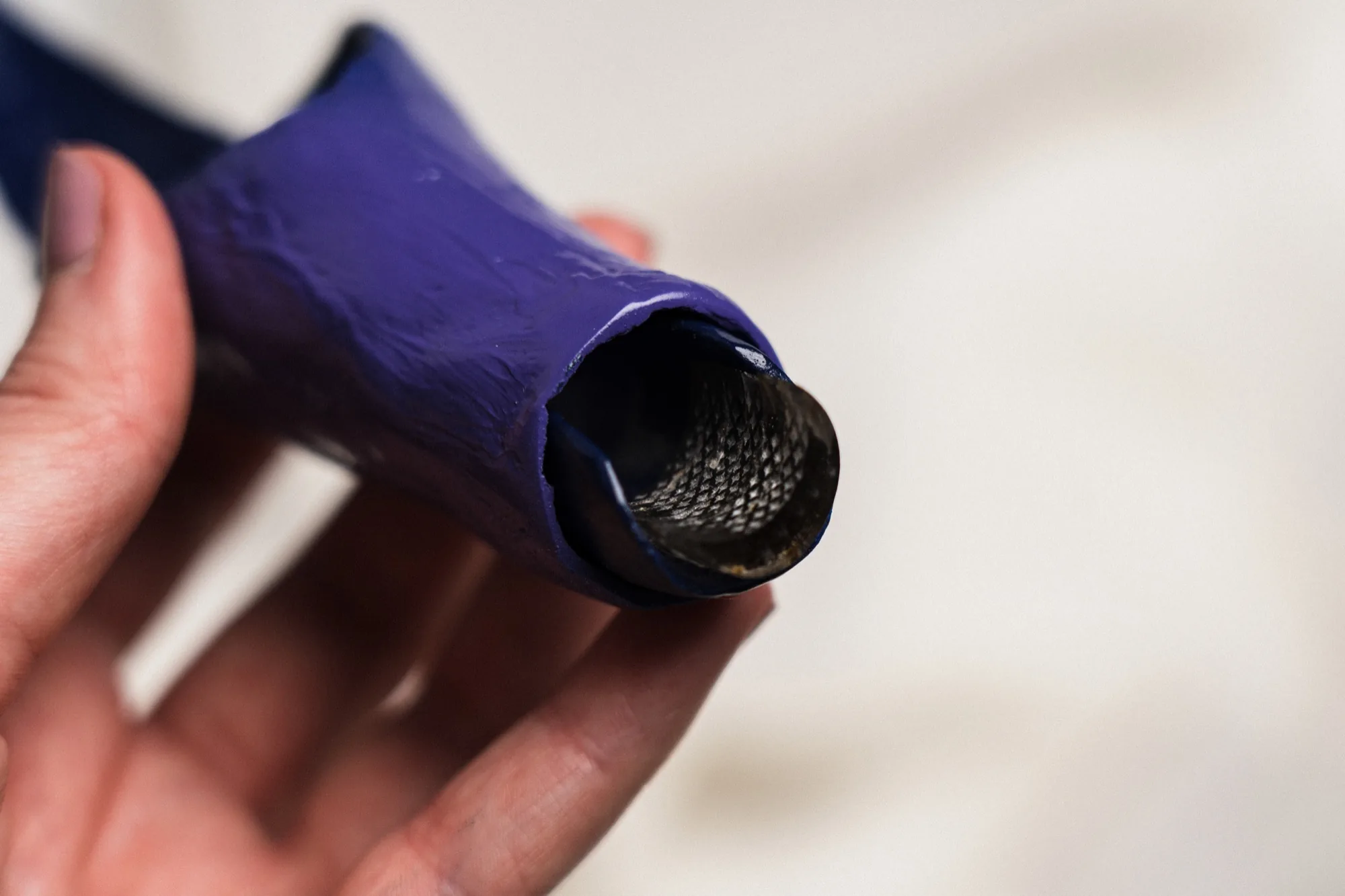 A hand holding the purple silicone applicator, showing the mesh interior