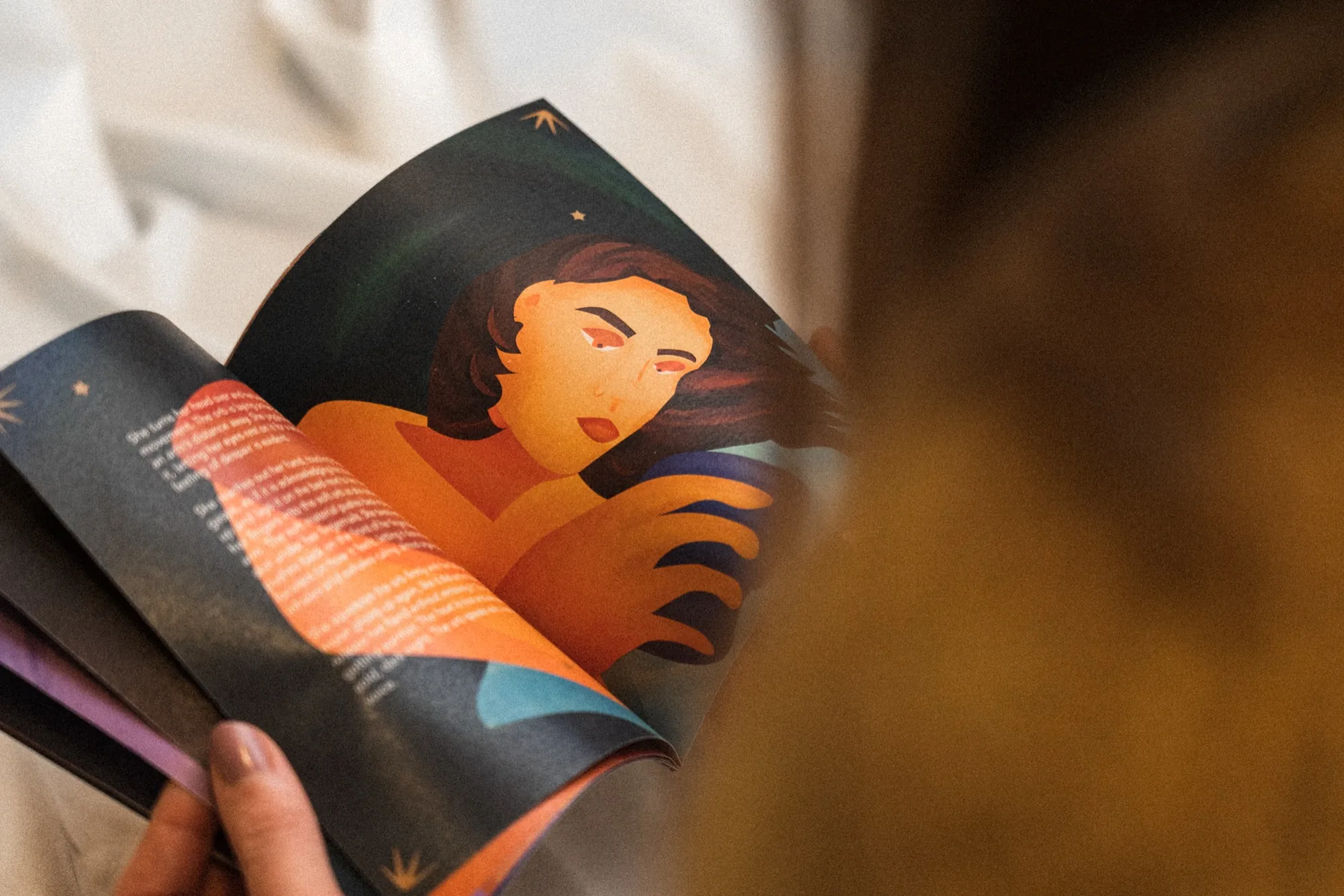 The illustrated booklet held open against a cream blanket